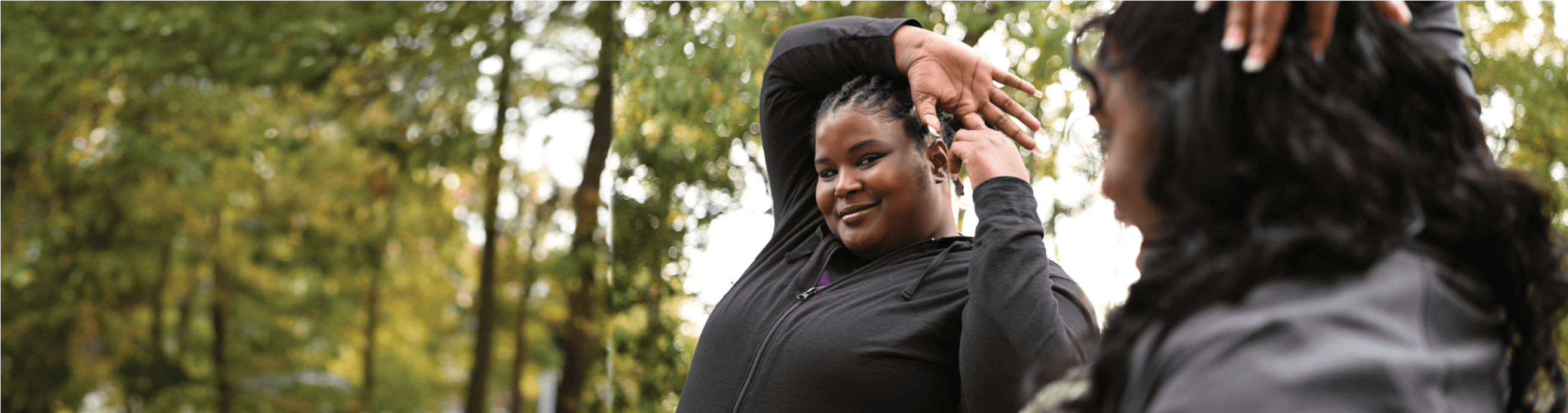 Nikki is stretching with a friend in the park.